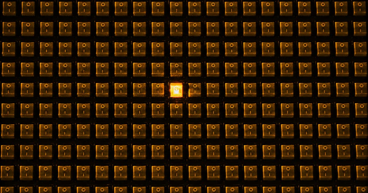 A dense, uniform grid of rectangular switches, with one near the center glowing significantly brighter than the surrounding switches.