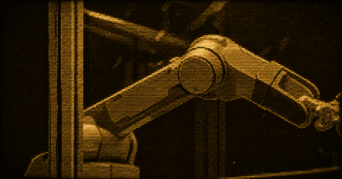 Industrial robotic arm behind a glass safety enclosure.