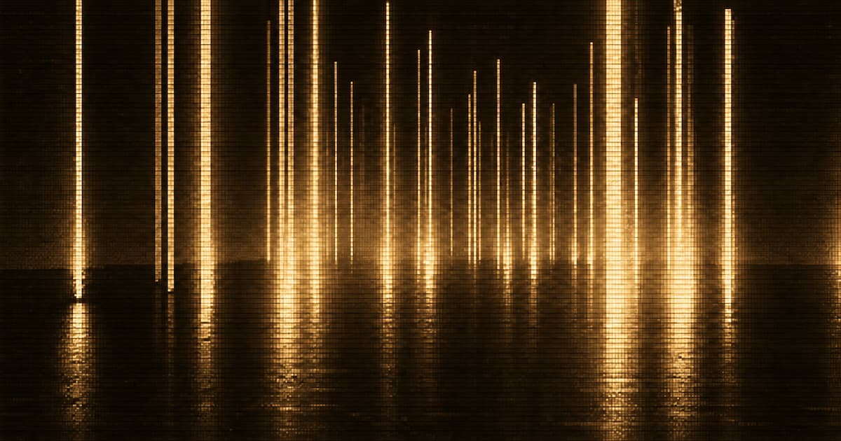 Vertical beams of light extend through a dark interior space and reflect across the floor, with smaller beams receding into the distance.