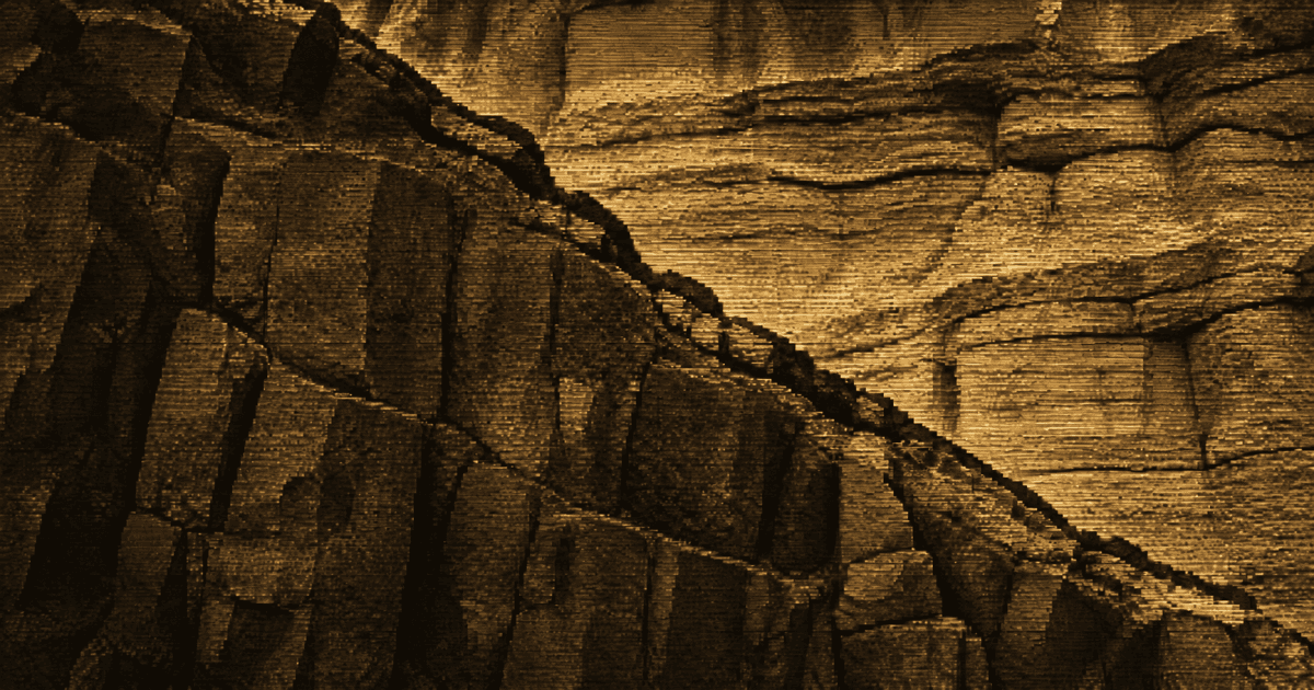 Close-up of two contrasting rock formations meeting along a prominent diagonal fault line across a rugged cliff face.